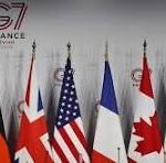 Row of national flags in front of a G7 France summit backdrop on a stage