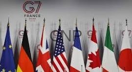 Row of national flags in front of a G7 France summit backdrop on a stage