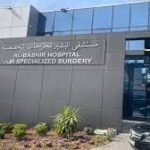 Exterior of a modern hospital entrance with a dark gray sign displaying large 'CNP' letters and smaller text above; glass facade and landscaping nearby.