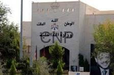 dakh - Center News Network Front view of a beige building with Arabic signage and emblem on the facade, surrounded by trees; a black-and-white portrait poster appears on the right side.