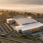 Aerial view of a white modern building labeled 'CNP' with extensive surrounding parking in a desert landscape.