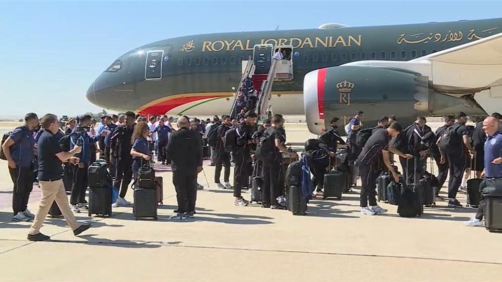 fais - Center News Network Passengers with rolling suitcases queue to board a Royal Jordanian airplane on the sunny tarmac.
