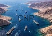 hormoz - Center News Network Aerial view of a busy shipping canal with several cargo ships moving through turquoise water between steep brown cliffs.