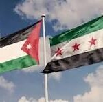 Two national flags waving in the wind: Jordan on the left and Syria on the right, against a blue sky with scattered clouds.