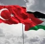 Turkish flag and Palestinian flag waving together against a cloudy sky, symbolizing solidarity between Turkey and Palestine.