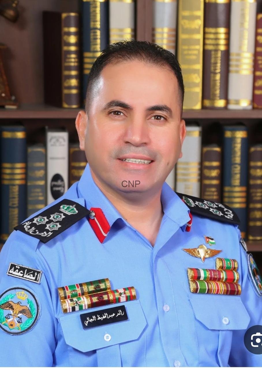 raed - Center News Network Portrait of a male officer in a light blue uniform with multiple ribbons and insignia, standing in front of a bookshelf full of legal tomes for an official portrait