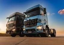 shahn - Center News Network Two large semi-trucks parked side by side on a desert highway at sunset.