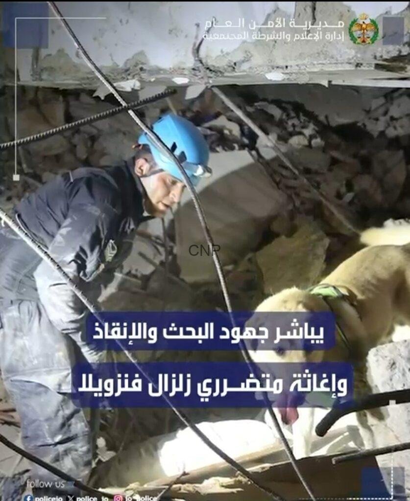 ss3 - Center News Network Rescue worker in a blue helmet searches rubble in a collapsed building; Arabic news banner overlays the scene with a dog nearby.