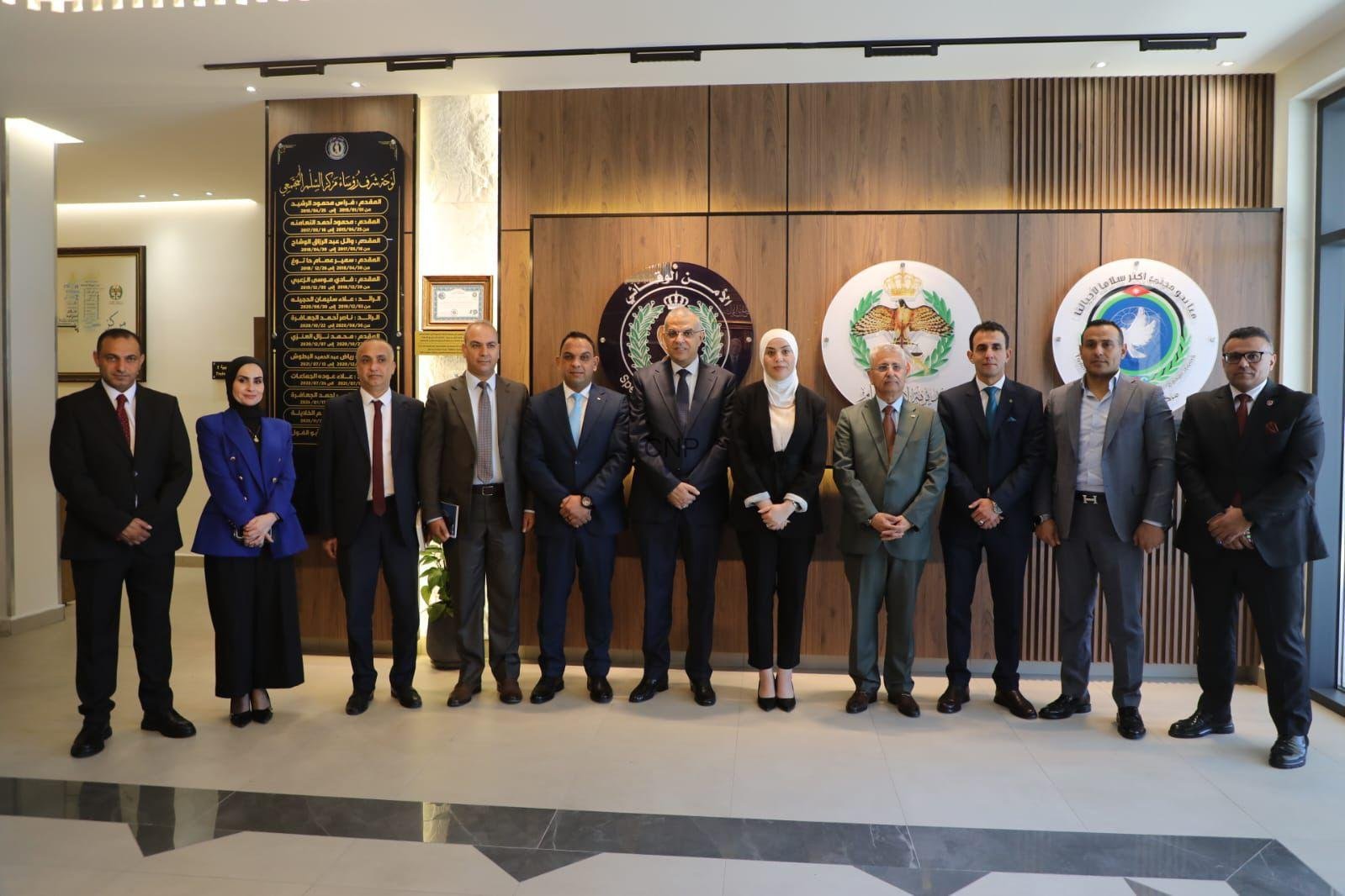 Group of ten professionals in formal attire standing in a lobby with wood panels and organizational emblems behind them.