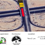 Aerial view of an unfinished highway interchange with looping ramps and a detour sign nearby.