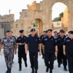 Group of uniformed security officers walking through a historic stone archway ruins at a sunlit site.