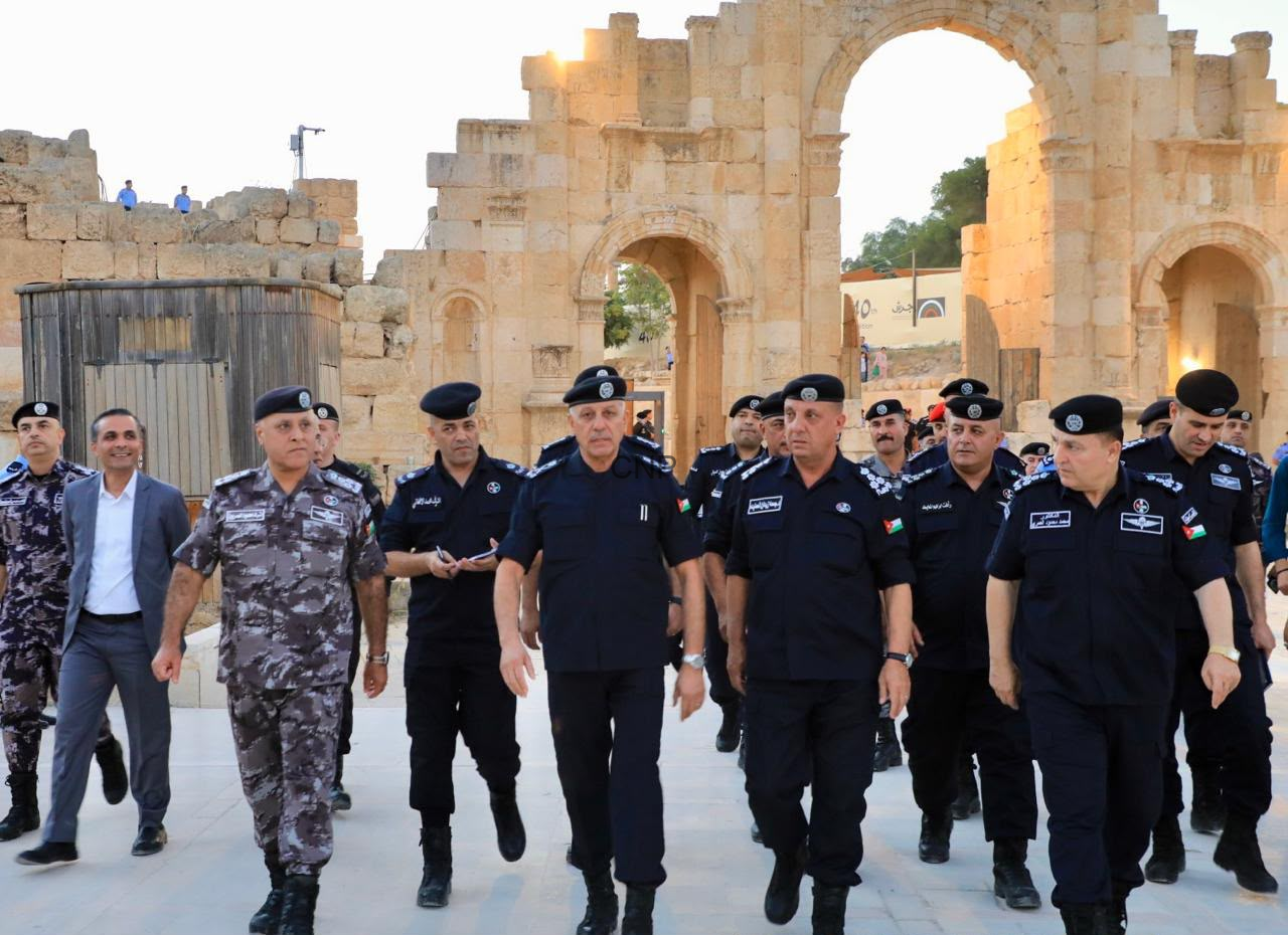 image - Center News Network Group of uniformed security officers walking through a historic stone archway ruins at a sunlit site.