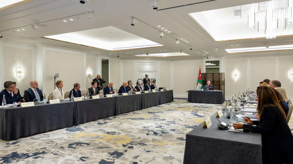 image - Center News Network Formal diplomatic meeting in a bright hotel ballroom; delegates sit along two long tables facing each other, Jordan flag at the head table.