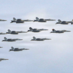 Formation of military fighter jets flying in the clear blue sky.