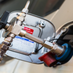 Fuel pump nozzle inserted into a car's fuel filler neck during refueling at a gas station