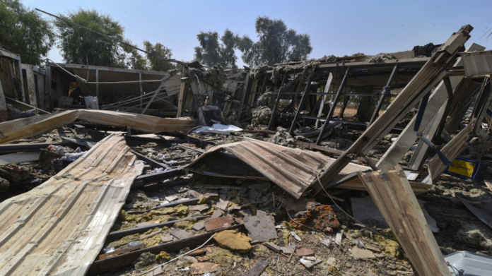 Rubble and twisted metal from a collapsed building, with scattered wooden panels and debris across the ground.
