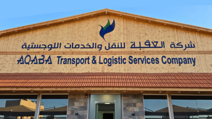 Facade of a wooden building with a blue logo and bilingual sign reading 'AQABA Transport & Logistic Services Company' (Arabic text above).