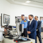 Group of officials and doctors in a lab, listening to a speaker at a medical device demonstration.