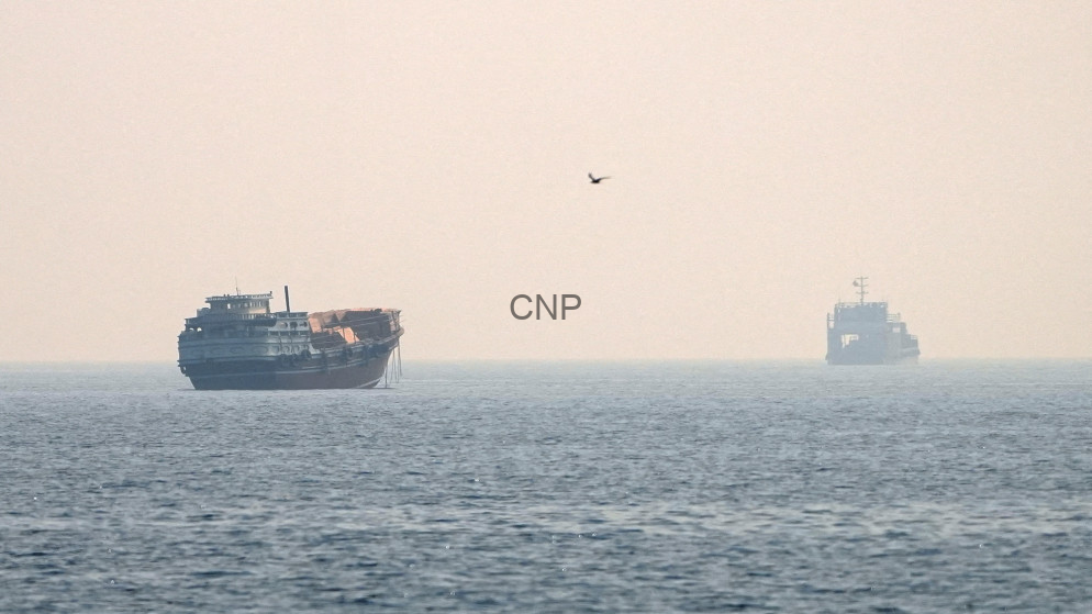 image - Center News Network Hazy seascape with a large ship on the left and a smaller vessel on the right, a single bird in the sky, and a centered 'CNP' watermark.