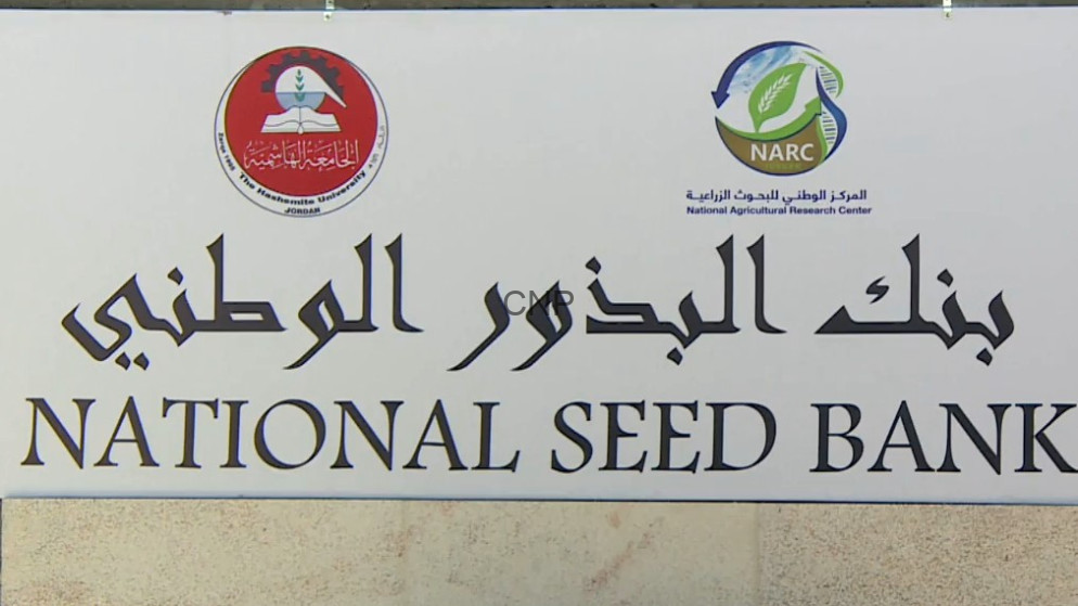 image - Center News Network Signboard for National Seed Bank with Arabic text and two circular logos above the English title on a pale wall.