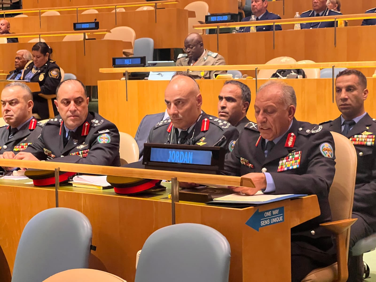 Row of high-ranking military officers in dress uniforms seated at a conference desk, 'JORDAN' nameplate in front of the central officer, badges and ribbons visible.