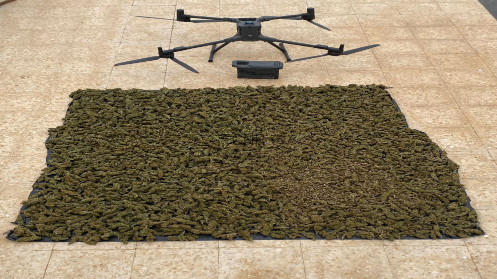 image - Center News Network Quadcopter drone hovering above a large sheet of dried cannabis laid out on a tarp on a tiled surface to document the harvest/seizure.