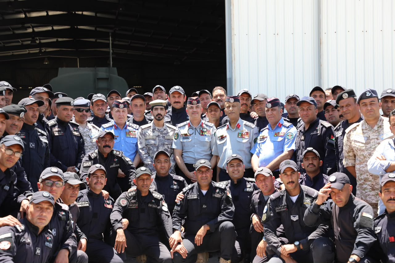 image - Center News Network Group of uniformed military personnel posing for a photo in front of a hangar.