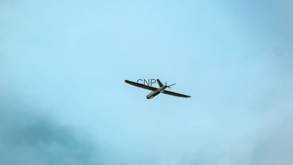 image - Center News Network Small propeller airplane seen from below, flying against a pale blue sky.