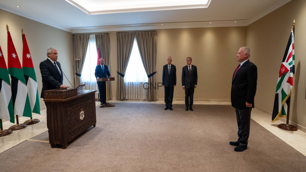 image - Center News Network Formal briefing: speaker at an ornately carved podium with Jordan flags on the left; four men in suits observe.