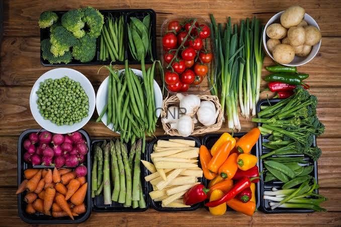 - Center News Network Assorted fresh vegetables arranged on a wooden surface, including broccoli, peas, green beans, cherry tomatoes, peppers, carrots, potatoes, and leafy greens.