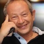 Smiling man on a mobile phone, talking, in a casual black shirt.