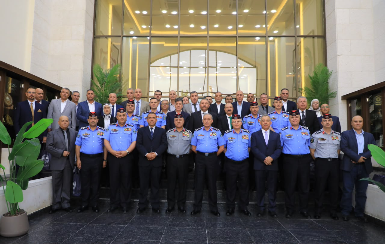 Group photo of uniformed officers in blue and gray uniforms with medals, and civilians in suits, posed outside a grand building entrance.