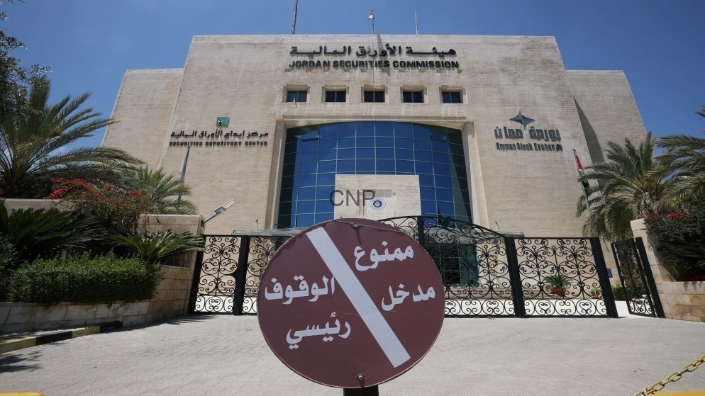 Front view of the Jordan Securities Commission building with a large circular Arabic no-entry sign at the gate and palm trees on both sides.