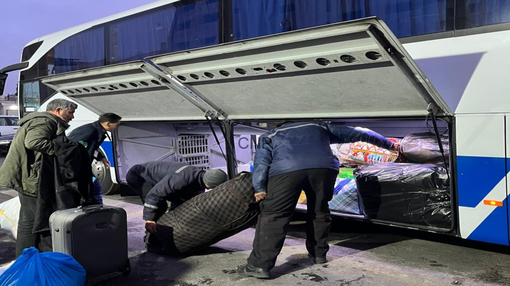 image - Center News Network People loading suitcases and bags into the luggage compartment of a white and blue bus.