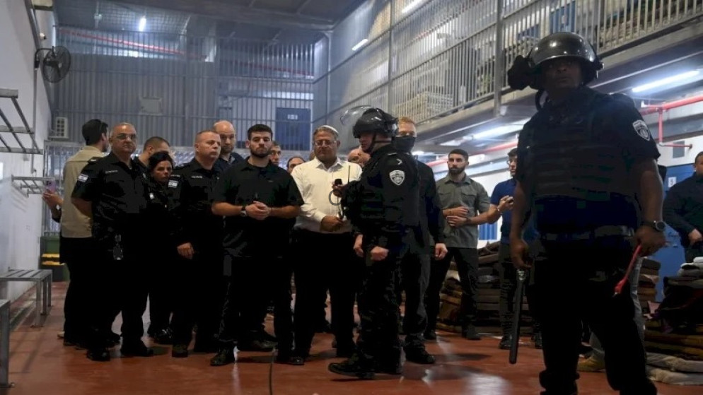 image - Center News Network Group of uniformed security officers in a workshop-like setting, listening to a demonstration; two officers in the foreground wear helmets and protective gear.