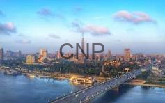 image - Center News Network Aerial view of a coastal city with a long bridge across a bay and a dense skyline under a blue sky with clouds; watermark 'CNP'.