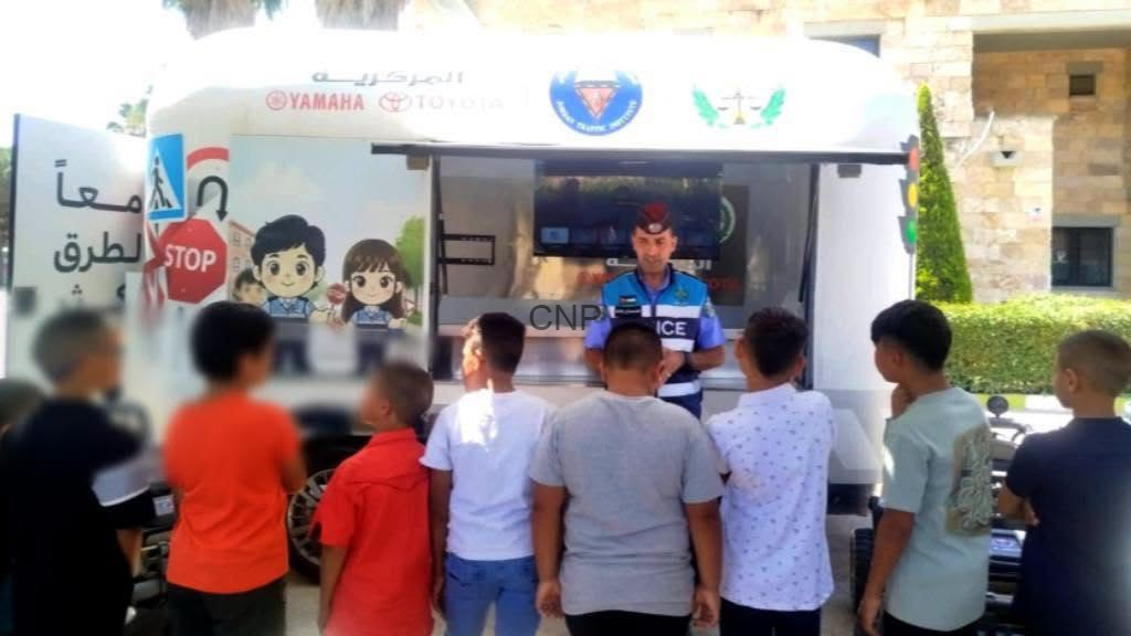 Police officer in a mobile outreach van addressing a group of children outdoors.
