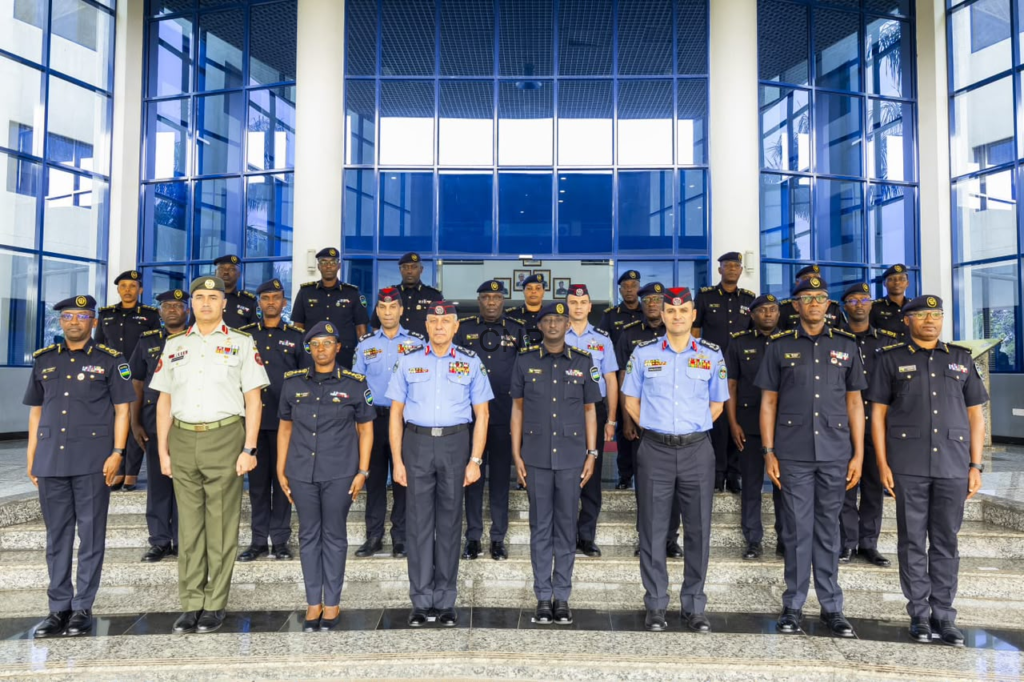 image - Center News Network Group of uniformed military officers posing for a formal photo on building steps outside a glass-fronted entrance.